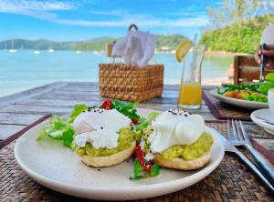 a plate of food on a table near the water at The Cove in Panwa Beach