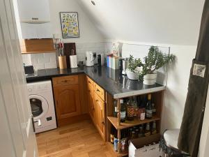 a small kitchen with a counter and a washer at 2 bedroom top floor flat, West Dulwich in London