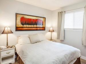 a bedroom with a white bed and a painting on the wall at Zena's By The Beach in Penticton