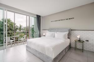 a bedroom with a white bed and a balcony at Sugar Ohana Poshtel in Kata Beach