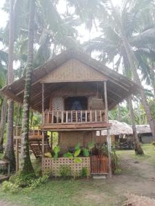 uma pequena cabana com um alpendre e palmeiras em Prince John beachfront cottages and Restaurant em San Vicente