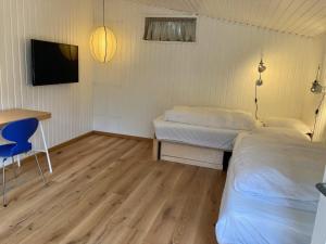 Habitación con 2 camas, escritorio y TV. en Holiday home Hornbæk II, en Hornbæk