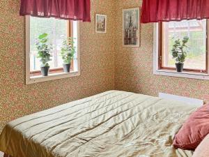 a bedroom with a bed and two windows with potted plants at 4 star holiday home in INGARÖ-By Traum in Grönskan