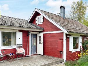 uma casa vermelha e branca com um deque de madeira em Holiday home RONNEBY XI em Ronneby