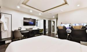 a bedroom with a bed and chairs and a television at Beyond Hotel in Incheon