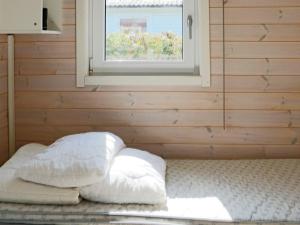 ein Bett mit weißen Kissen in einem Zimmer mit Fenster in der Unterkunft Holiday home LAHOLM in Laholm