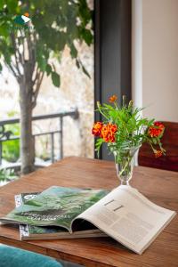 a book and a vase with flowers on a table at Charm Hill Sapa Hotel in Sa Pa