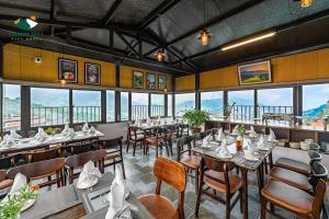 een restaurant met tafels, stoelen en ramen bij Charm Hill Sapa Hotel in Sa Pa