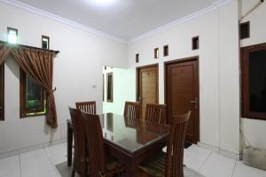 a dining room with a wooden table and chairs at OYO 93188 Soren Hotel And Coffee in Lawean