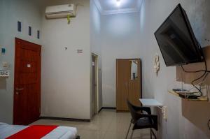 Zimmer mit einem Bett und einem TV an der Wand in der Unterkunft OYO 93186 HKP Homestay in Blitar