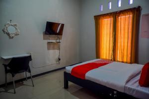 a bedroom with a bed and a television and a window at OYO 93186 HKP Homestay Syariah in Blitar