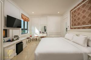 a white bedroom with a large bed and a kitchen at Toàn Thắng Hotel HN - by Bay Luxury in Trương Lâm