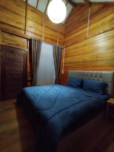 1 dormitorio con 1 cama con pared de madera en Mandalika Queen Hostel, en Kuta Lombok