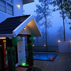 a house with a swimming pool at night at Pabis luxurious stay in Vythiri