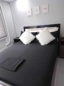 a black bed with two white pillows on it at Aloha Hale One Oasis Cdo in Cagayan de Oro