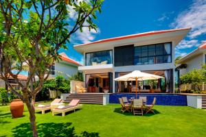 Casa con patio con sillas y sombrilla en The Ocean Resort, en Da Nang