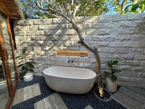 a bathroom with a white bath tub next to a stone wall at ONAYA Bali Resort - Adults Only in Uluwatu