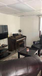 a living room with a piano and a leather couch at cozzy room with private entrance and drive way in Arlington