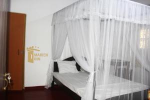 a bed with white curtains in a room at Marien Inn in Galle