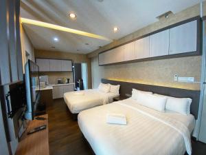 a hotel room with two beds and a flat screen tv at Aeropod Cactus Rail Suite With Balcony - Kota Kinabalu in Kota Kinabalu