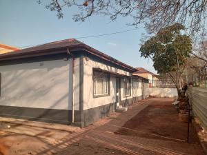 a small white building with a door on a street at Las Palmas Day & Night Guest House in Pretoria