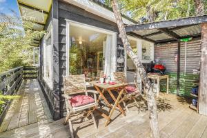 a patio with a table and chairs on a deck at The Treehouse - Raglan Holiday Studio in Raglan