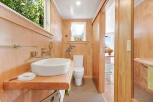 a bathroom with a sink and a toilet at The Treehouse - Raglan Holiday Studio in Raglan