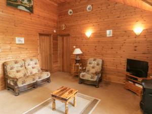 uma sala de estar com duas cadeiras e uma televisão em Acorn Lodge em Mydrim