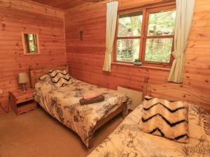 MydrimにあるAcorn Lodgeのログキャビン内のベッドルーム1室(ベッド2台付)