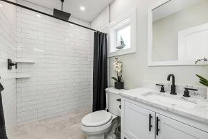 a white bathroom with a toilet and a shower at Renovated & Sophisticated Home Near Beach & Shops! in Barnstable