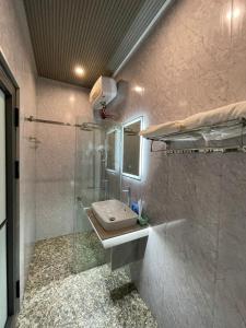 y baño con lavabo y ducha acristalada. en Homestay T&T - Căn hộ gia đình, en Da Nang