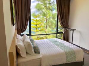 a bedroom with a bed and a large window at Mountain Valley Resort in Kundasang
