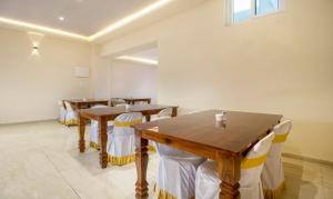 a dining room with wooden tables and white chairs at Treebo Trend Cool River in Visakhapatnam