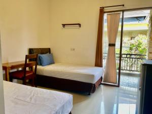 a bedroom with two beds and a desk and a window at Frog Homestay Sanur in Sanur