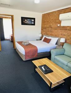 a hotel room with a bed and a couch and a table at Moama Central Motel in Echuca