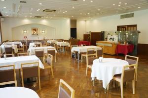 uma sala de jantar com mesas e cadeiras brancas em 北軽井沢　Golden Forest Hotel em Naganohara