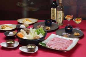 a table with plates of food and a bottle of wine at 北軽井沢　Golden Forest Hotel in Naganohara