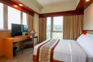 a hotel room with a bed and a desk with a television at Sotogrande Hotel Baguio in Baguio