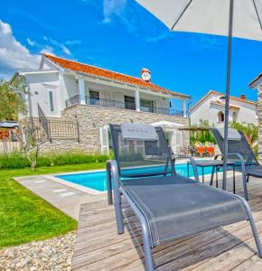 un patio con una silla y una sombrilla junto a la piscina en Salt & Sand Villa, en Kornić