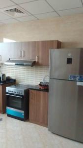 eine Küche mit einem Kühlschrank aus Edelstahl und Holzschränken in der Unterkunft Sunset villa in Fudschaira