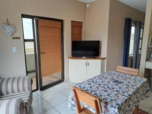 ein Wohnzimmer mit einem Tisch und einem TV in der Unterkunft Desert Pearl Self catering & Accommodation in Walvis Bay