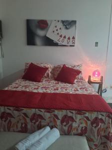 a bedroom with a bed with red pillows and a playing cards picture at Aconchegante Lapa in Rio de Janeiro