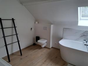 a bathroom with a white tub and a toilet at Le Refuge de Toine Gîte rural 3 épis in Chimay