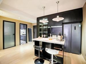 una cocina con armarios negros y una barra con taburetes en Datong Elite Apartment, Peoples Square, CBD, en Shanghái