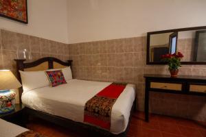 a small bedroom with a bed and a mirror at Hotel del Sol in San Miguel de Allende