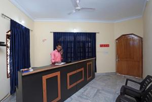 a man is standing at a reception desk at Goroomgo Pink Villa Guest House Bhubaneswar in Bhubaneshwar