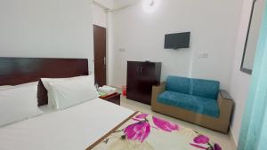 een slaapkamer met een bed en een blauwe stoel bij Hotel City Panthapath in Dhaka