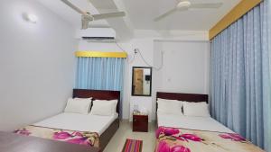 two beds in a room with blue curtains at Hotel City Panthapath in Dhaka