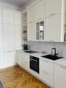 a white kitchen with white cabinets and a sink at LittleParis in Cluj-Napoca