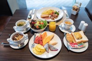 a wooden table with plates of food and cups of coffee at Admiral Premier Bangkok in Bangkok